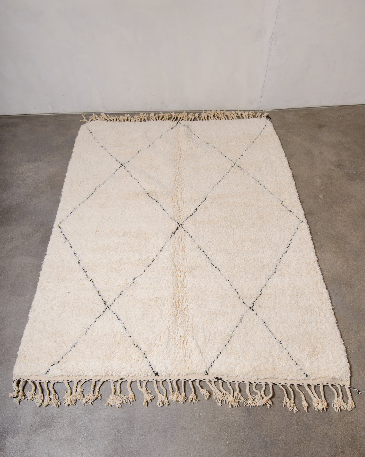 Berberlin Beniourain rug with black line design laying flat on concrete floor.